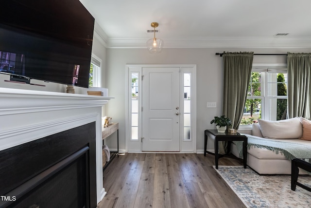 foyer featuring wood finished floors, ornamental molding, and baseboards