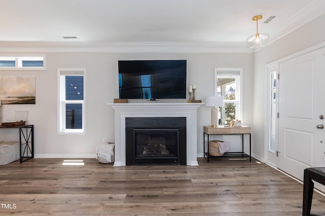 living room featuring ornamental molding, wood finished floors, baseboards, and a glass covered fireplace