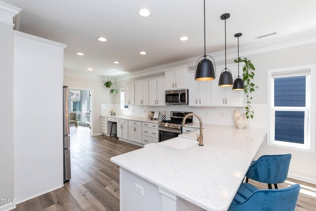 kitchen featuring appliances with stainless steel finishes, ornamental molding, backsplash, a sink, and a peninsula