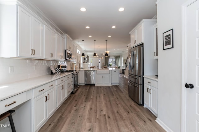 kitchen with appliances with stainless steel finishes, a peninsula, recessed lighting, white cabinetry, and open floor plan
