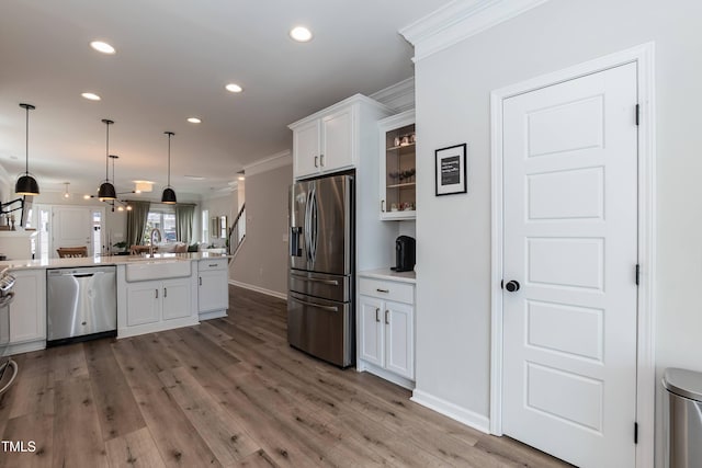 kitchen featuring appliances with stainless steel finishes, a sink, ornamental molding, open floor plan, and white cabinetry