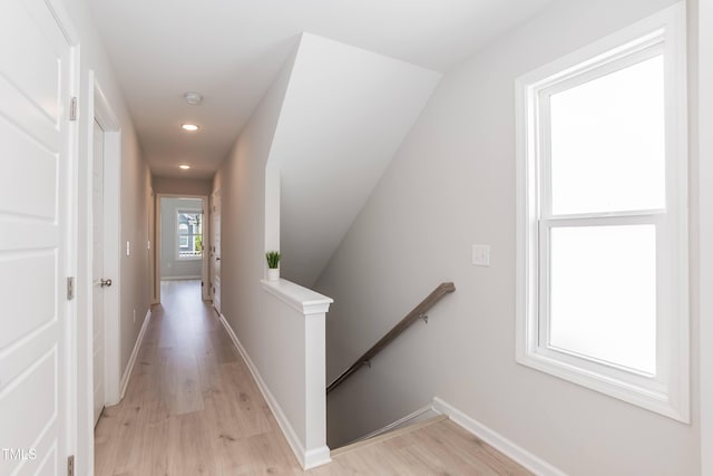 hallway with an upstairs landing, light wood-style floors, recessed lighting, and baseboards