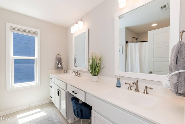 full bath featuring tile patterned floors, healthy amount of natural light, double vanity, and baseboards