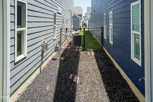 view of home's exterior with fence, central AC unit, and a gate