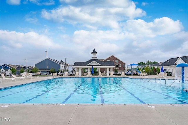 community pool with fence, a patio, and a residential view