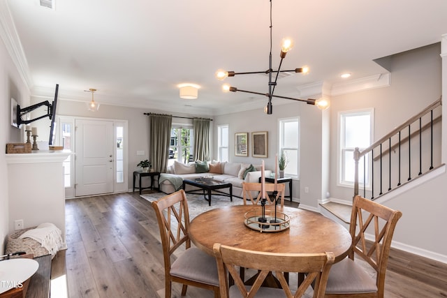dining space with a chandelier, crown molding, wood finished floors, stairway, and baseboards