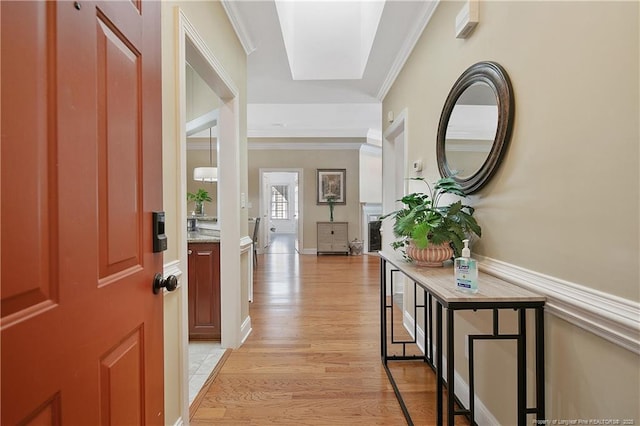 foyer entrance with crown molding and light wood finished floors