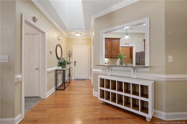 corridor featuring crown molding, light wood-style floors, and baseboards