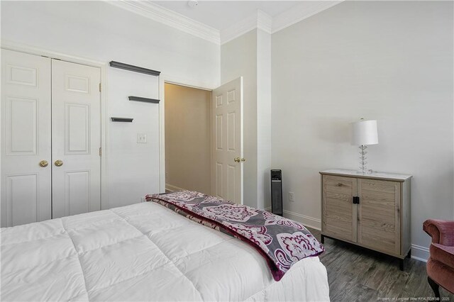 bedroom featuring baseboards, a closet, crown molding, and dark wood-style flooring
