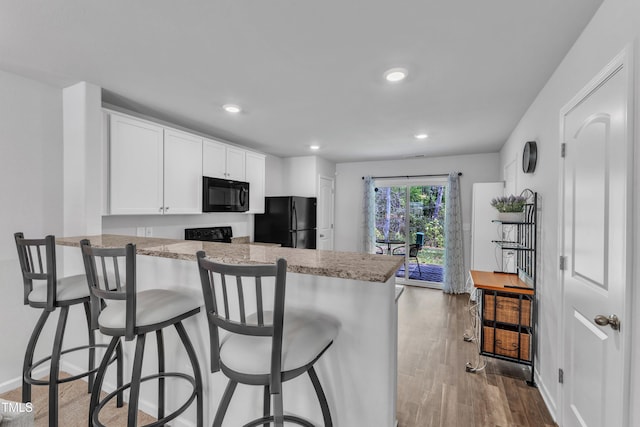 918 E Green St Unit F105, Franklinton, NC 27525 - kitchen featuring recessed lighting, a kitchen breakfast bar, black appliances, a peninsula, and white cabinetry
