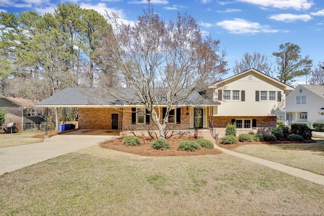 tri-level home featuring brick siding, concrete driveway, a front yard, and a carport
