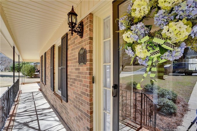 doorway to property with brick siding and a porch