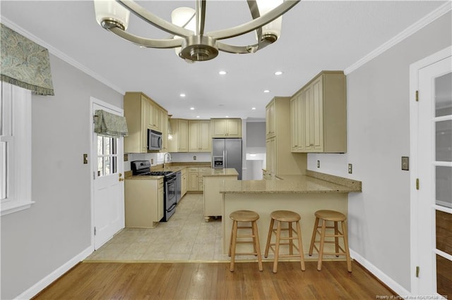 kitchen featuring crown molding, light wood finished floors, a peninsula, stainless steel appliances, and baseboards