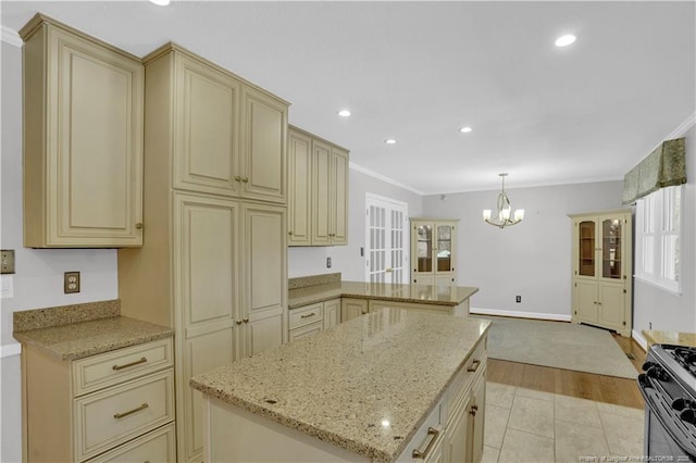 kitchen featuring cream cabinetry, a peninsula, crown molding, gas stove, and a notable chandelier