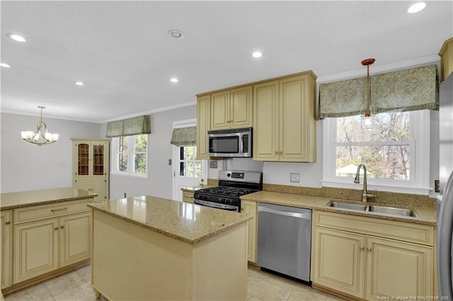 kitchen featuring ornamental molding, a center island, cream cabinetry, a sink, and appliances with stainless steel finishes