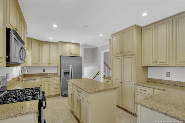 kitchen featuring cream cabinets, light stone countertops, a sink, and stainless steel appliances