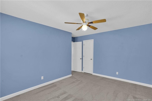 carpeted empty room featuring baseboards, ceiling fan, and a textured ceiling