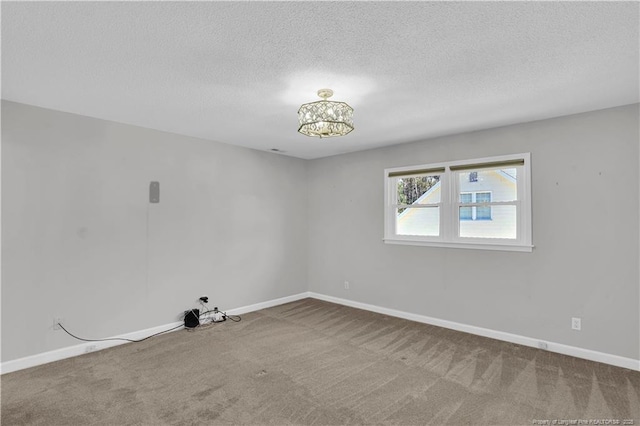 empty room featuring carpet floors, baseboards, and a textured ceiling