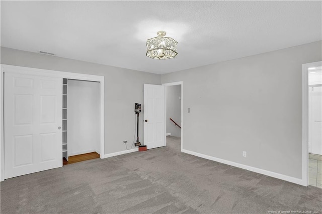 unfurnished bedroom featuring baseboards, visible vents, a closet, and carpet