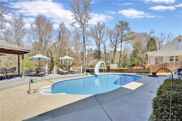 view of swimming pool with a patio, fence, a fenced in pool, and a water slide