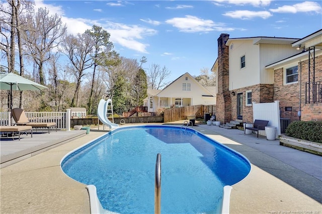 view of pool featuring a patio area, a fenced in pool, a water slide, fence, and entry steps