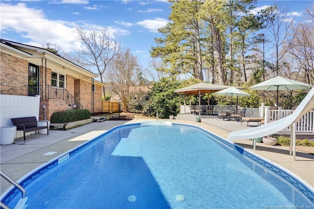 view of swimming pool with a fenced in pool, a water slide, fence, and a patio area