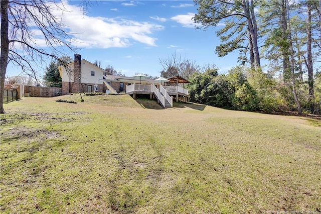 view of yard featuring fence, a wooden deck, and stairway