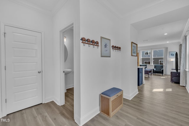 hallway featuring light wood-style flooring, baseboards, and crown molding