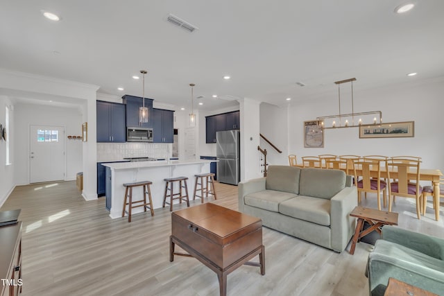 living area featuring a chandelier, crown molding, visible vents, and light wood-style flooring