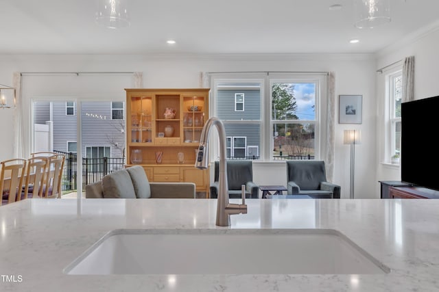 kitchen with light stone counters, a sink, ornamental molding, and recessed lighting