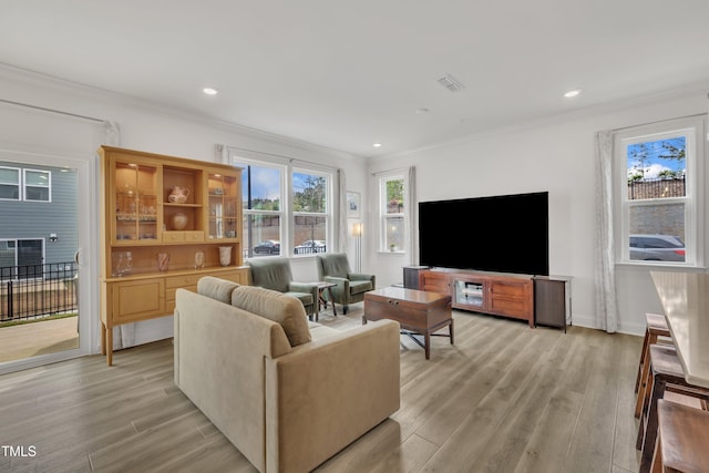 living area with light wood-type flooring, ornamental molding, and recessed lighting