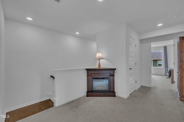 unfurnished living room featuring baseboards, a glass covered fireplace, carpet, and recessed lighting