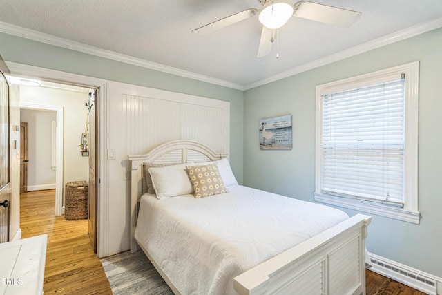 418 S 2nd St, Smithfield, NC 27577 - bedroom with baseboards, a baseboard heating unit, ornamental molding, and light wood-style flooring