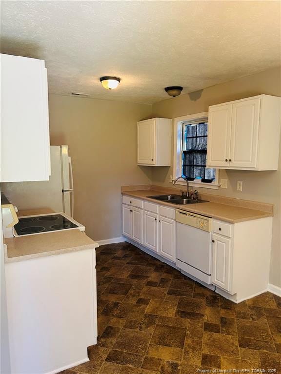 kitchen featuring baseboards, white appliances, white cabinetry, and a sink