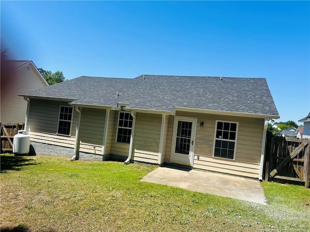back of house with a patio, fence, a yard, and roof with shingles