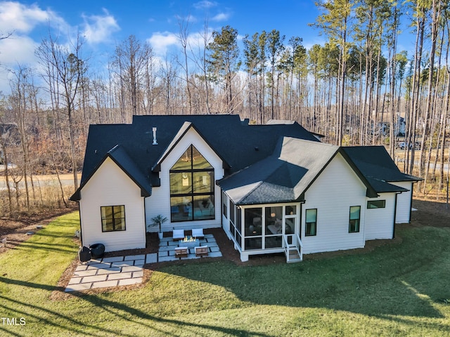 back of property with a lawn, a sunroom, roof with shingles, and a patio area
