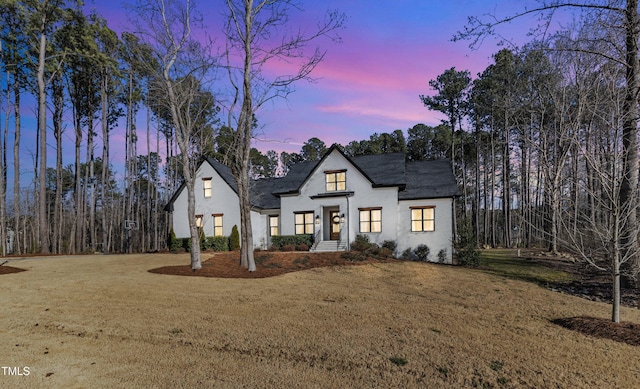 modern inspired farmhouse with stucco siding and a lawn