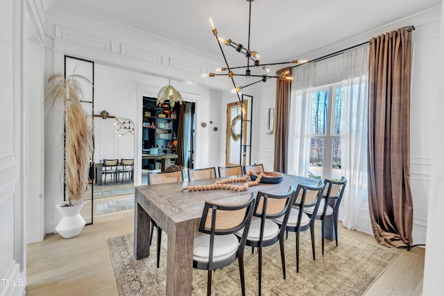 dining space featuring light wood-type flooring and a notable chandelier