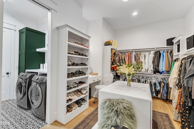 walk in closet with separate washer and dryer and light wood-style floors