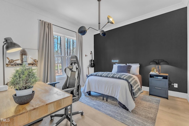 bedroom with baseboards, light wood-style floors, and an accent wall