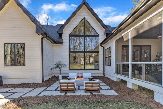 back of property featuring an outdoor living space with a fire pit, roof with shingles, and a patio area