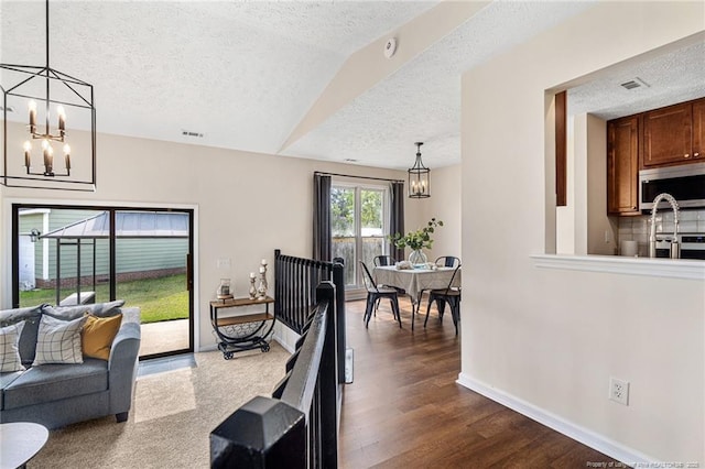 6611 Brannan Way, Fayetteville, NC 28314 - living room with a textured ceiling, a chandelier, dark wood-style flooring, and baseboards