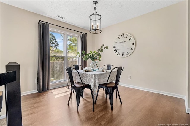 6611 Brannan Way, Fayetteville, NC 28314 - dining room featuring wood finished floors, a chandelier, baseboards, and a textured ceiling