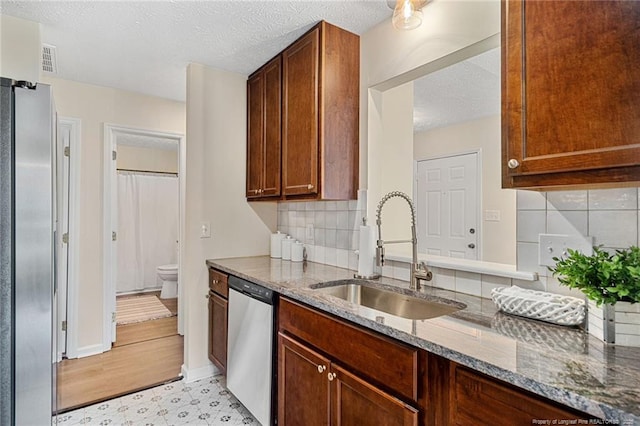 6611 Brannan Way, Fayetteville, NC 28314 - kitchen featuring appliances with stainless steel finishes, a sink, stone countertops, decorative backsplash, and a textured ceiling