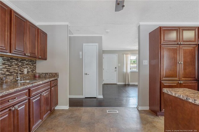 6026 Cornish St, Fayetteville, NC 28314 - kitchen featuring a sink, tasteful backsplash, a textured ceiling, baseboards, and stone countertops