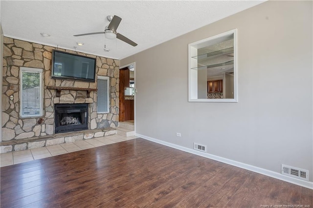 6026 Cornish St, Fayetteville, NC 28314 - unfurnished living room with ceiling fan, wood finished floors, a textured ceiling, baseboards, and a stone fireplace