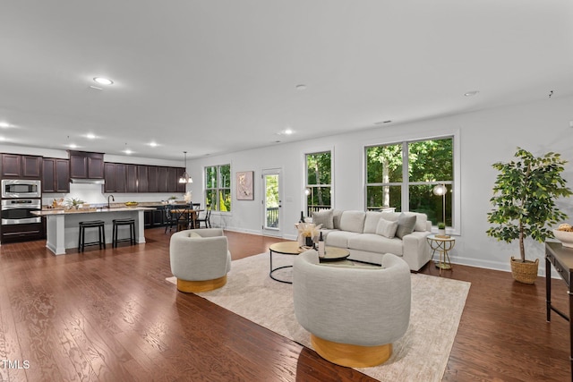 living area featuring recessed lighting, plenty of natural light, dark wood-style floors, and baseboards