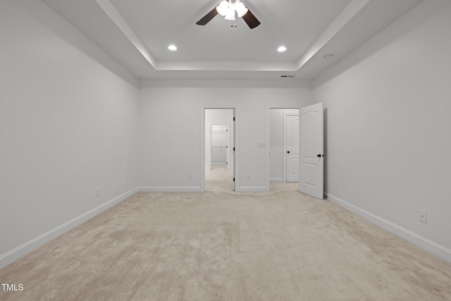 unfurnished bedroom with a raised ceiling, light carpet, baseboards, recessed lighting, and connected bathroom