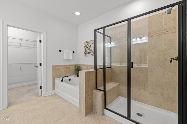 full bath featuring a shower stall, a garden tub, a walk in closet, tile patterned flooring, and recessed lighting