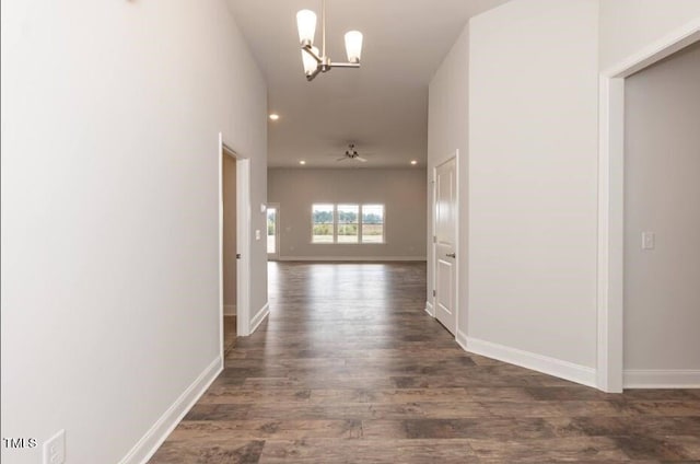 hall featuring a chandelier, dark wood-style floors, recessed lighting, and baseboards